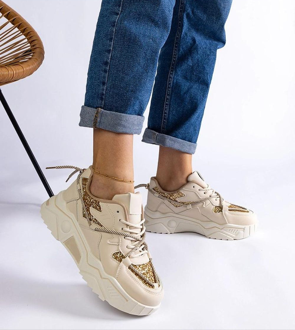 Stylish cream and gold chunky sneakers with denim jeans, highlighting modern casual fashion footwear.
