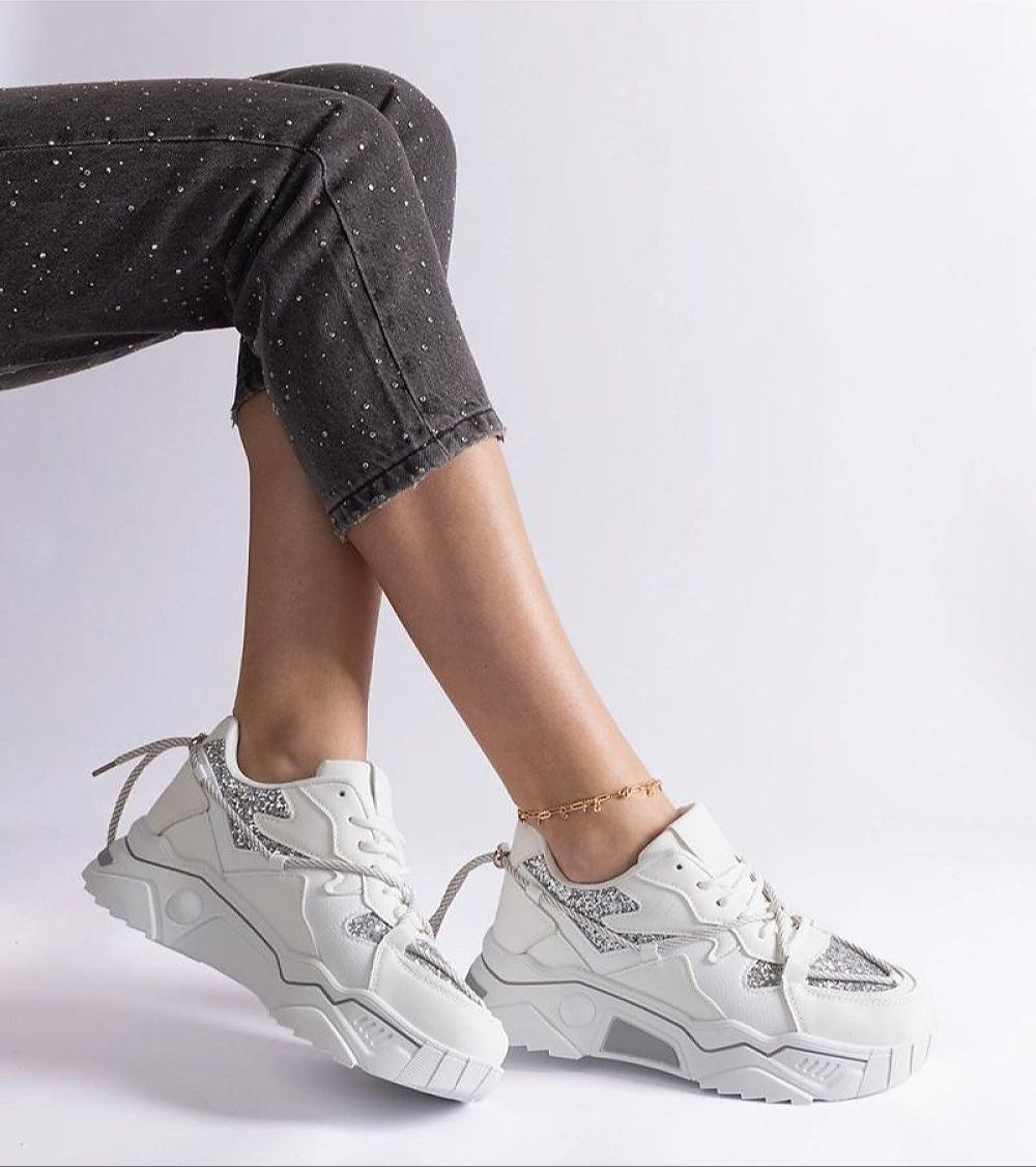 White chunky sneakers on model with speckled black pants, showcasing a trendy footwear style for modern fashion enthusiasts.
