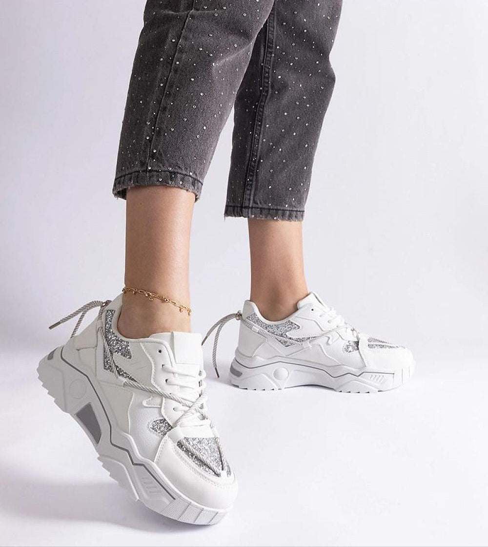 White chunky sneakers with silver accents styled with dark jeans