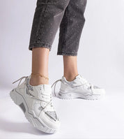 White chunky sneakers with silver accents styled with dark jeans