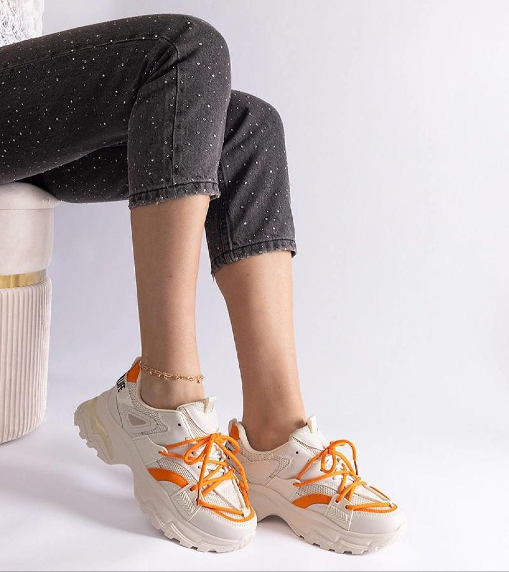 Person wearing Selvyna Contrast Sport Sneakers with orange accents, showcasing eco leather upper and supportive sole.