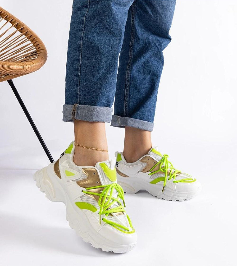 Person wearing vibrant green and white sneakers paired with rolled-up blue jeans, showcasing modern sporty footwear design.