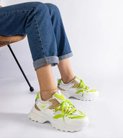 Person wearing Selvyna Contrast Sport Sneakers with neon accents and eco leather, sitting on a chair with legs crossed.