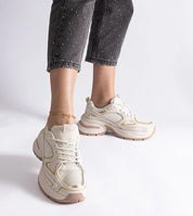 Woman wearing Elphira white chunky sole sneakers with eco leather upper and gray rubber platform, paired with speckled black jeans.