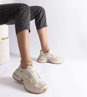 Woman wearing white chunky sneakers with thick sole, sitting in a stylish pose, showcasing modern casual fashion footwear.