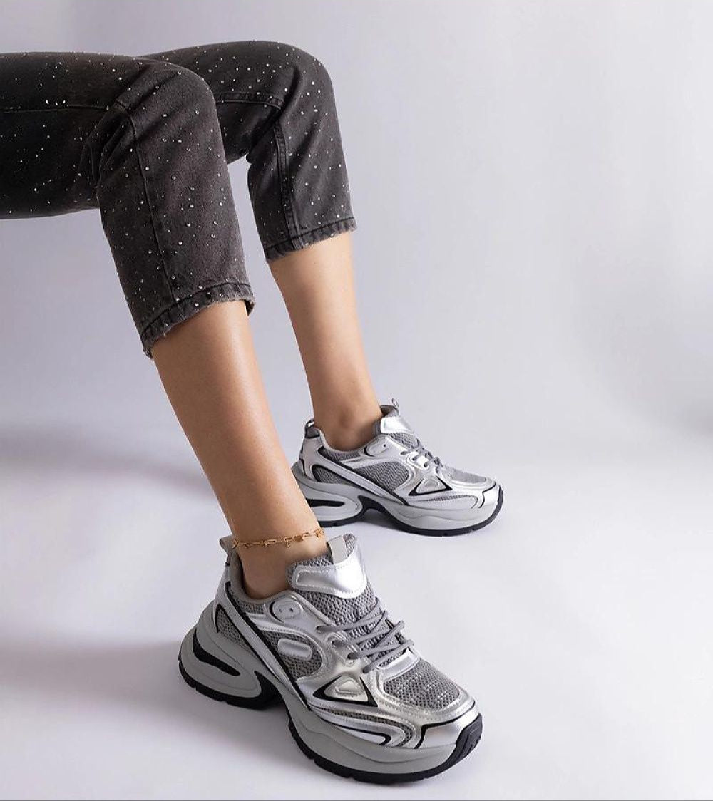 Woman wearing gray chunky sole sneakers with speckled black pants, showcasing modern design and comfort.