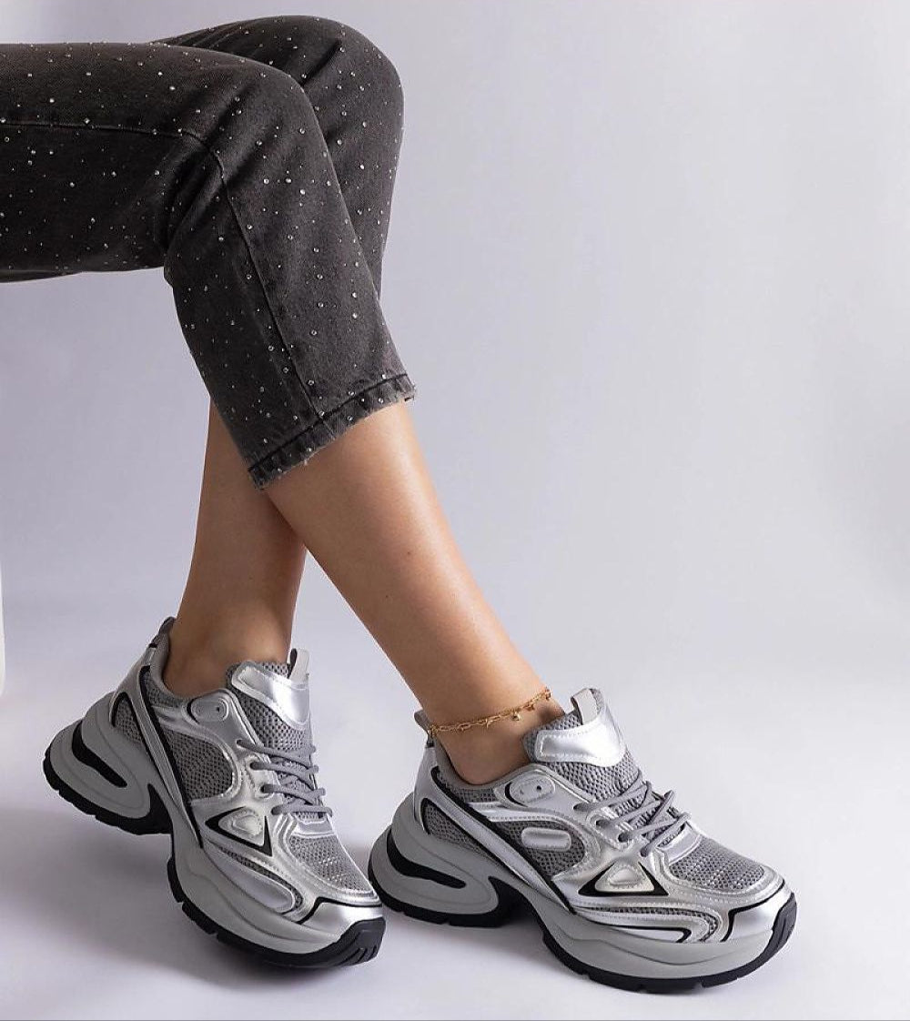 Person wearing metallic chunky sneakers with black sole, paired with cropped pants.