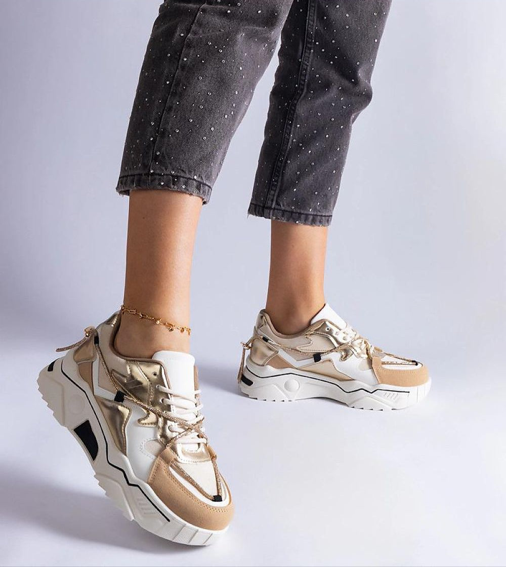 Stylish brown and white sneakers with crystal details on a woman's feet, featuring a chunky sole and lace-up design.