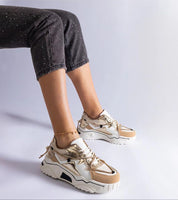 Woman wearing stylish beige and white sneakers with chunky soles, paired with black speckled pants, showcasing a modern casual look.
