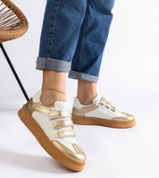 Person wearing Elurea Gold Velcro Street Sneakers in eco leather with golden sheen, brown rubber sole, showcasing casual street style.