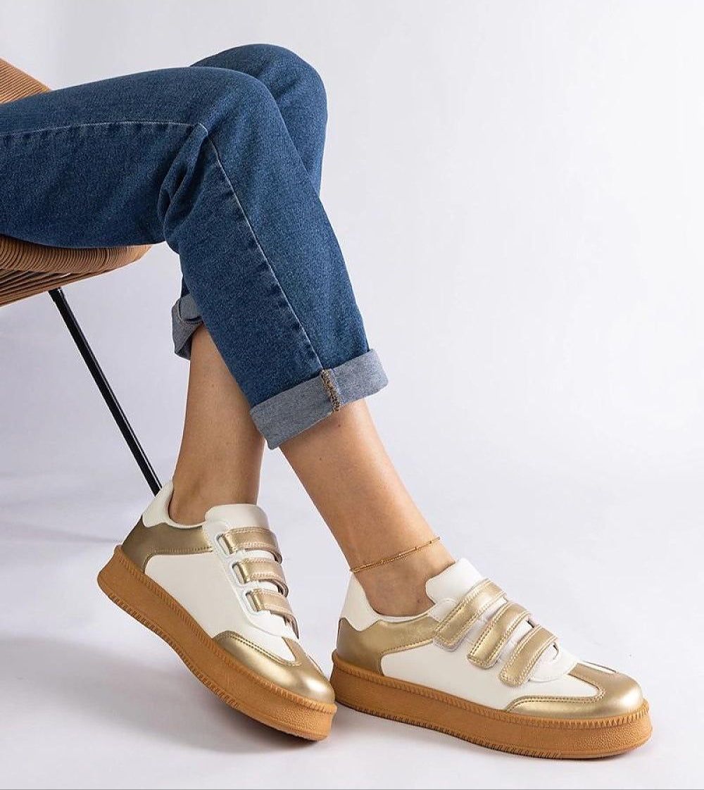 Person wearing Elurea Gold Velcro Street Sneakers with eco leather and brown sole, sitting on a chair with legs crossed.