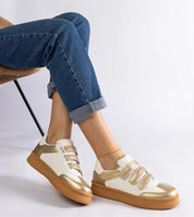 Person wearing Elurea Gold Velcro Street Sneakers with eco leather and brown sole, sitting on a chair with legs crossed.