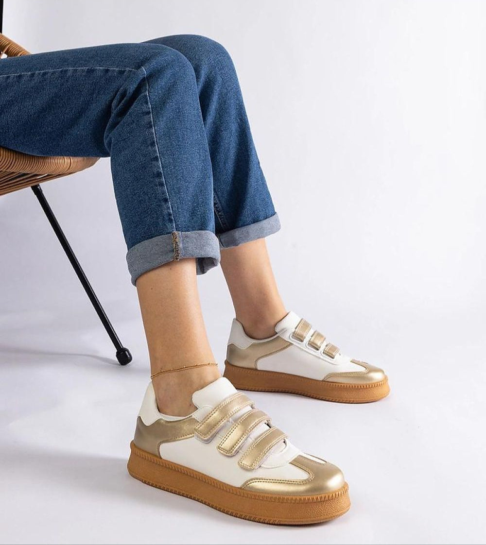 Person wearing Elurea Gold Velcro Street Sneakers with a golden sheen, eco leather, and brown rubber sole for everyday elegance.