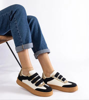 Person wearing Elurea Gold Velcro Street Sneakers with denim jeans, showcasing sleek eco leather design and brown rubber sole.