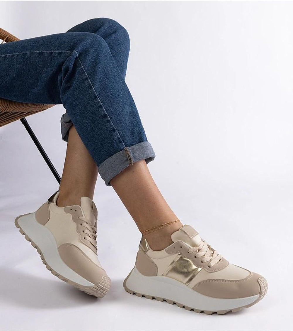 Person wearing Veressa Minimal Platform Sneakers with beige rubber platform and tonal design, styled with cuffed jeans sitting on chair.
