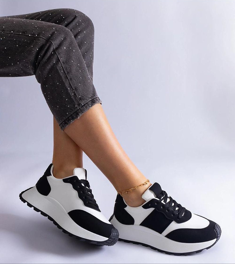 Person wearing black and white platform sneakers with casual pants. Ideal for minimalist fashion and everyday versatility.