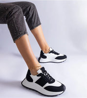 Person wearing black and white minimalist platform sneakers with cuffed pants, showcasing modern and versatile footwear style.