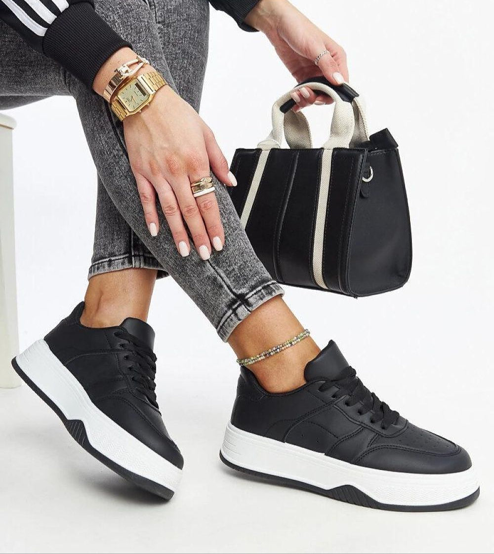 Woman wearing Kaedira Bold Platform Sneakers with a black leather bag, showcasing urban style with elevated sole and eco leather design.