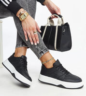 Woman wearing Kaedira Bold Platform Sneakers with a black leather bag, showcasing urban style with elevated sole and eco leather design.