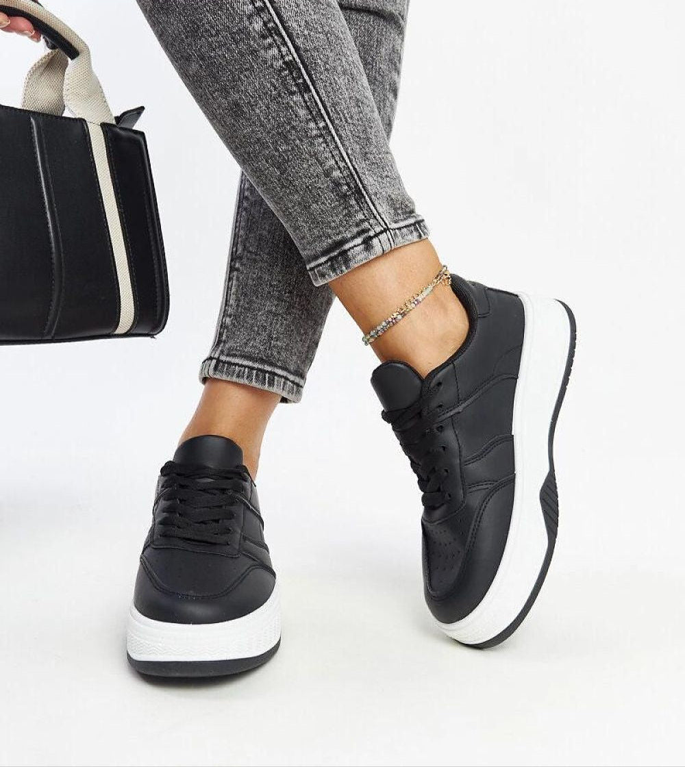 Black Kaedira Bold Platform Sneakers with eco leather upper and elevated sole styled with grey denim and black bag.