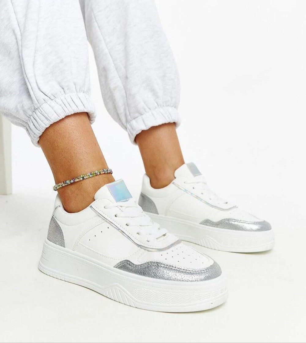 Person wearing Norevia Silver-Edged Sneakers with silver accents and chunky white sole, showcasing urban style and modern edge.