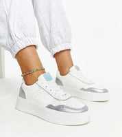 Person wearing Norevia Silver-Edged Sneakers with silver accents and chunky white sole, showcasing urban style and modern edge.