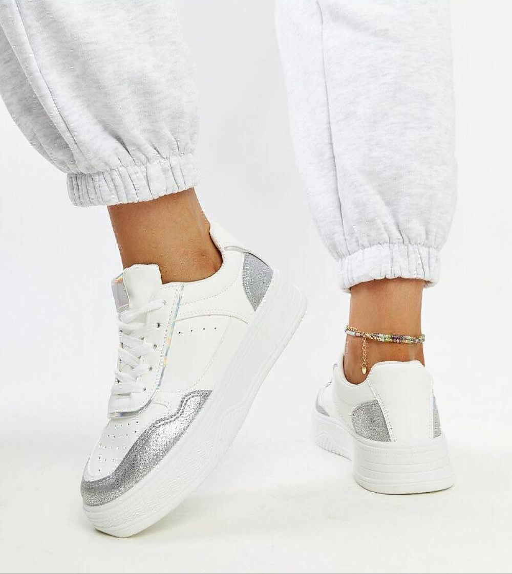Norevia silver-edged sneakers with chunky white soles and matte eco leather detail, styled with casual pants.
