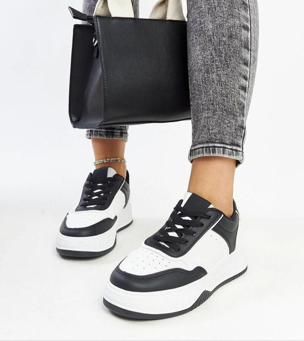 Person wearing Vartema platform sneakers in black and white eco suede leather with chunky soles, paired with grey jeans and a black bag.