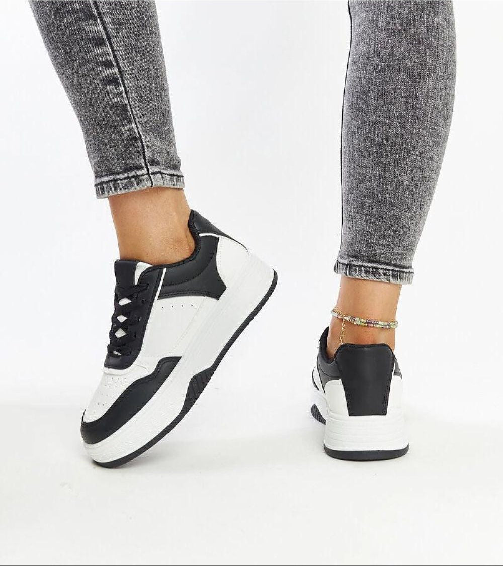 Person wearing Vartema platform sneakers in black and white eco suede leather with chunky sole, shown with gray jeans.