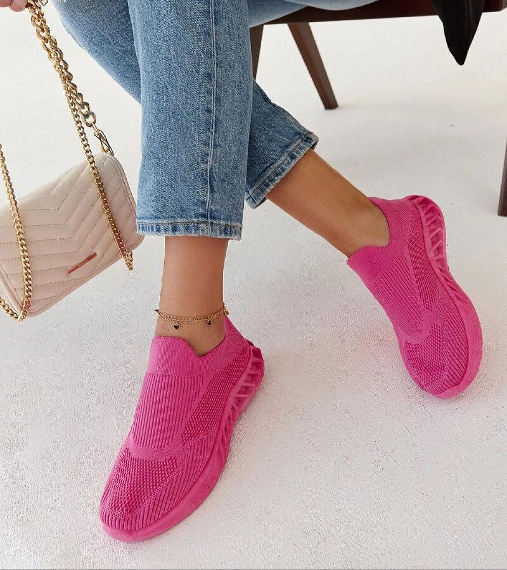 Woman wearing pink Zavella Slip-On Sport Knit Sneakers with jeans, highlighting breathable and flexible design ideal for summer.