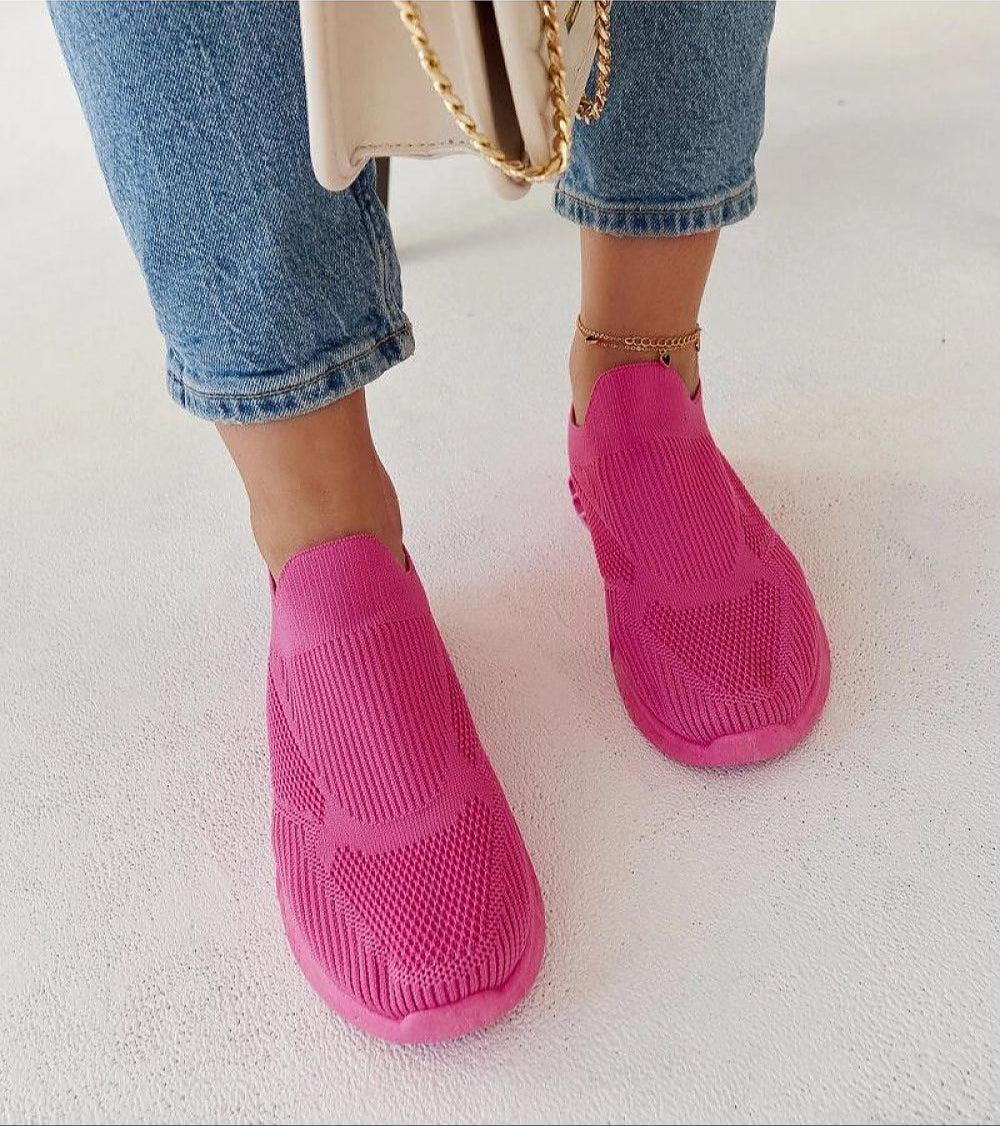 Woman wearing pink Zavella Slip-On Sport Knit Sneakers with jeans and a handbag.