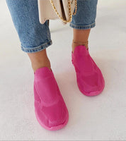 Woman wearing pink Zavella Slip-On Sport Knit Sneakers with jeans and a handbag.