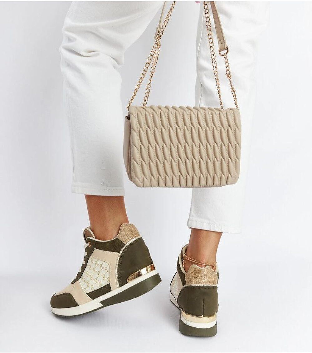 Fashionable wedge sneakers paired with white pants and a stylish quilted beige handbag, showcasing modern casual elegance.