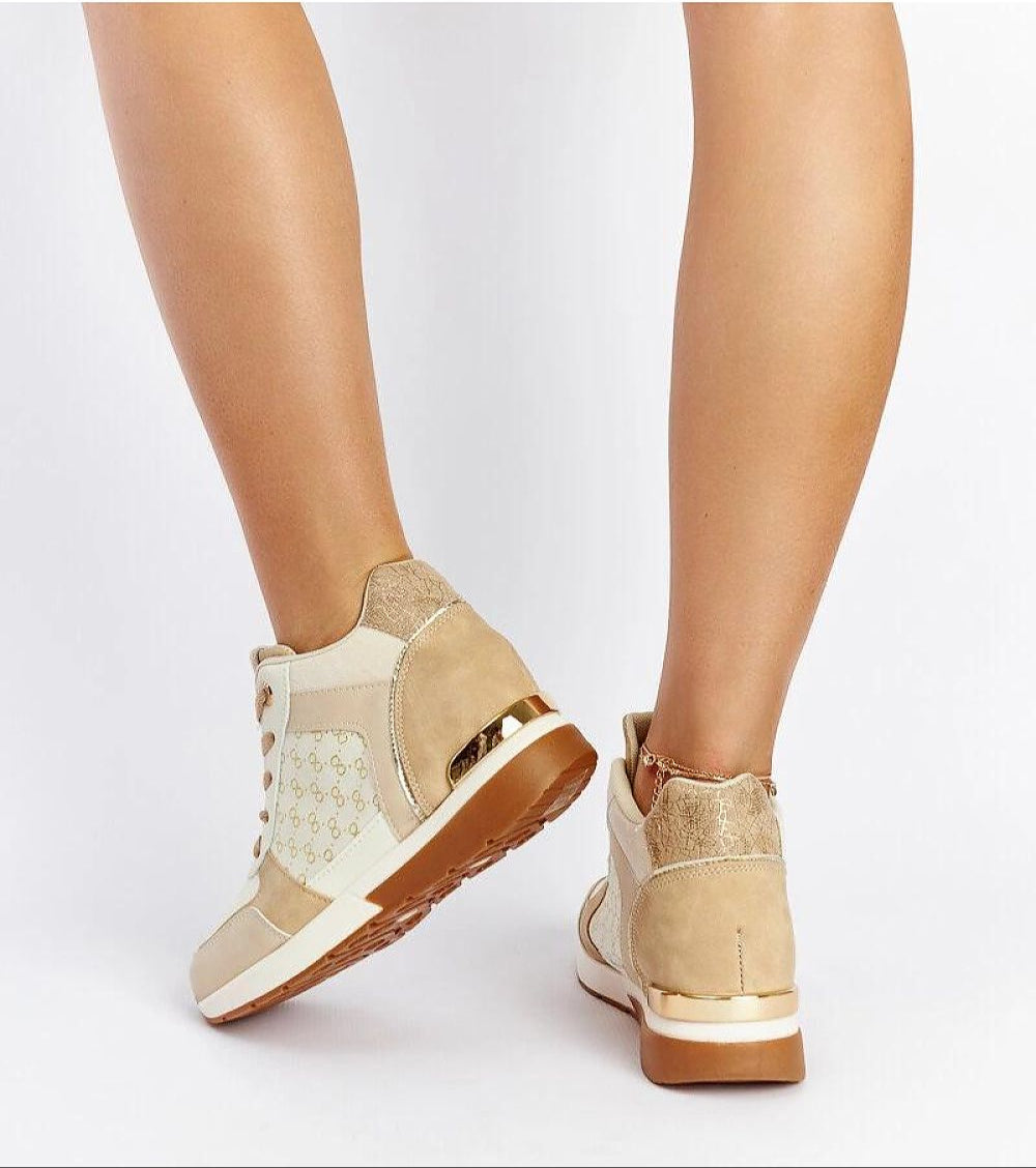 Person wearing beige and white wedge sneakers with gold trim, showcasing back view and ankle details on a white background.