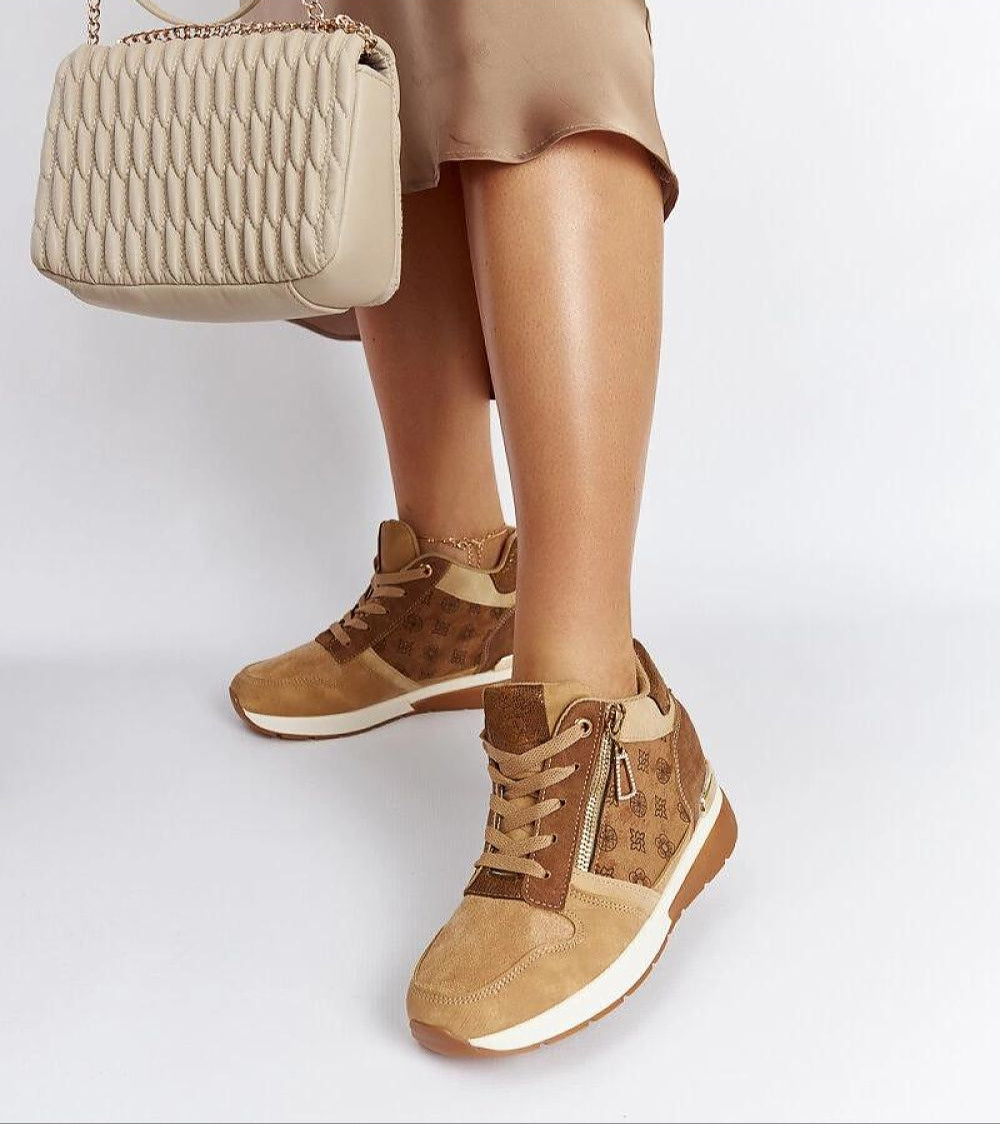 Woman wearing Valterra Brown Wedge Sneakers with eco-leather, 8 cm heel, paired with a beige purse, showcasing sporty and stylish elegance.