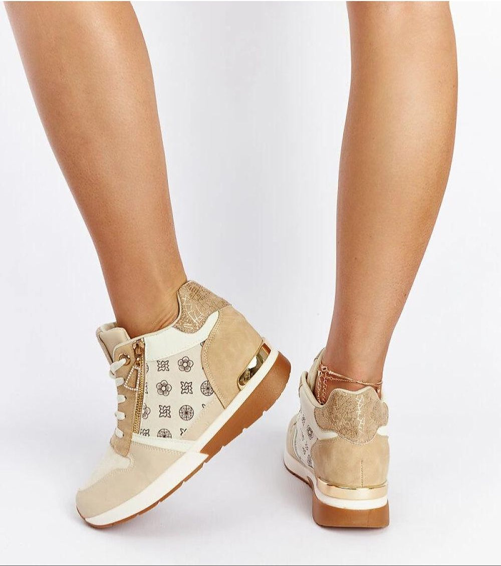 Person wearing stylish beige wedge sneakers with white and metallic details, showcasing a modern casual look.