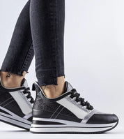 Black glitter Glevara platform sneakers on feet, showcasing elevated sole and lace-up design against a white background.