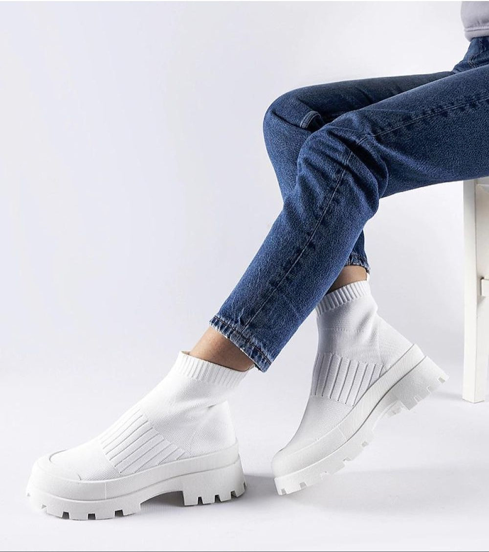 Woman wearing Velvone Slip-On Platform Sneakers with all-white finish, paired with blue jeans, showcasing casual style and comfort.