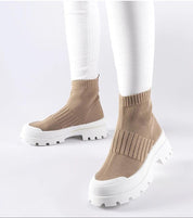 Person wearing beige Velvone slip-on platform sneakers with white jeans, showcasing flexible textile upper and elevated sole.
