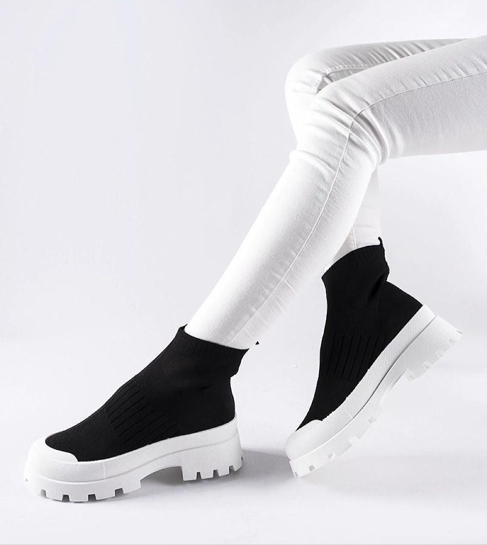 Person wearing black Velvone Slip-On Platform Sneakers with white pants, showcasing modern style and comfort for casual wear.