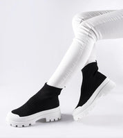Person wearing black Velvone Slip-On Platform Sneakers with white pants, showcasing modern style and comfort for casual wear.