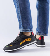 Person wearing Lirano lightweight summer sneakers in black with colorful details, paired with blue jeans, showcasing the sneaker's style.