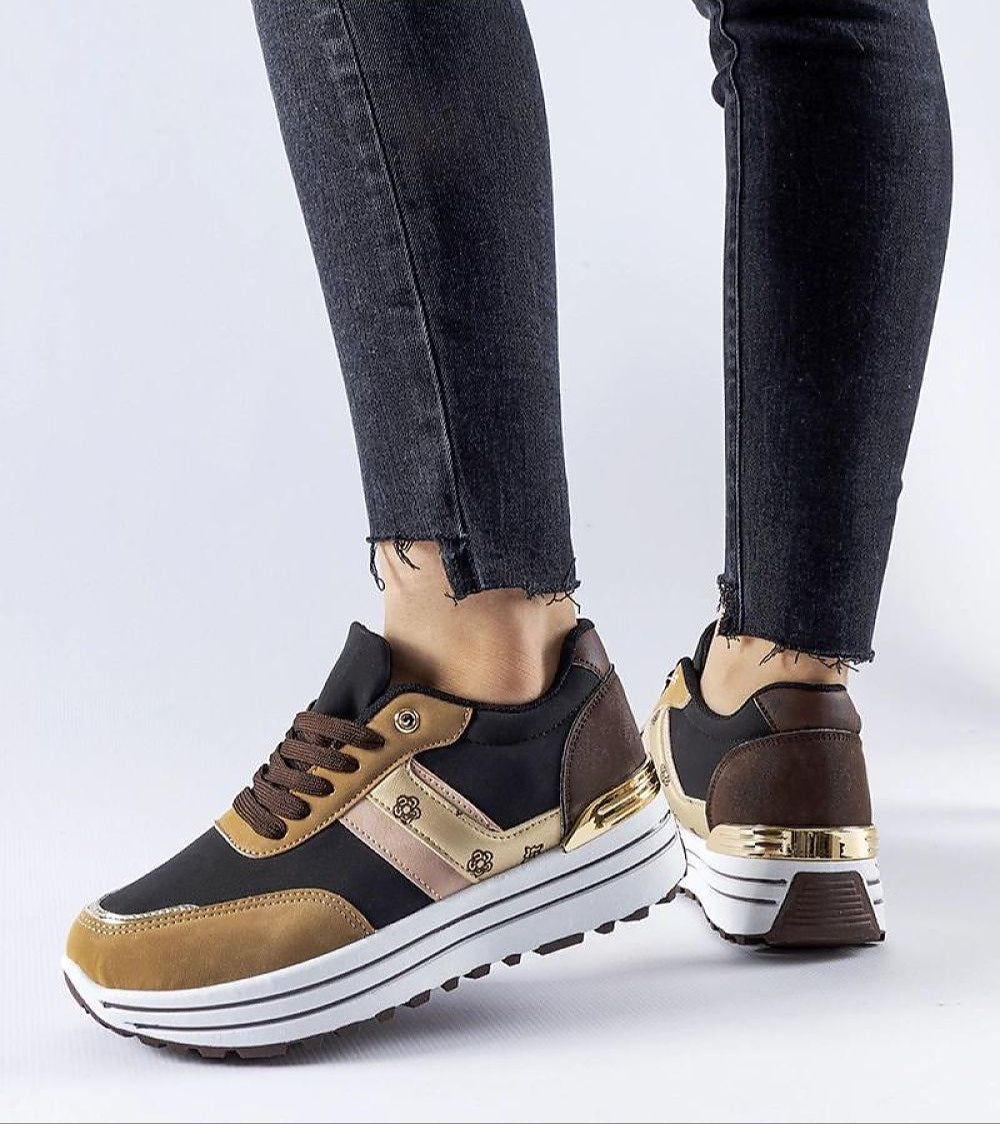 Person wearing brown suede lace-up sneakers with platform sole and black jeans.