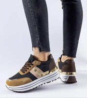 Person wearing brown suede lace-up sneakers with platform sole and black jeans.