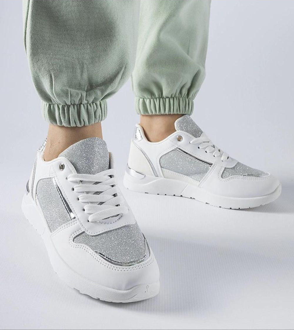 White and silver lace-up sneakers worn with green pants, showcasing a modern design and comfortable fit perfect for casual outings.