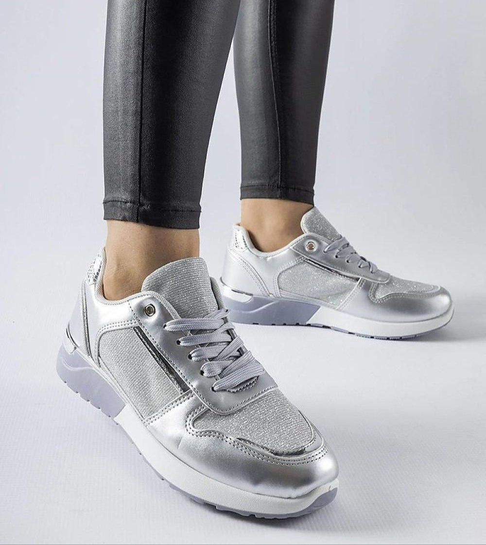 Silver lace-up sneakers with a sleek design and comfortable fit, paired with black leggings on a white background.