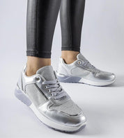 Silver lace-up sneakers with a sleek design and comfortable fit, paired with black leggings on a white background.