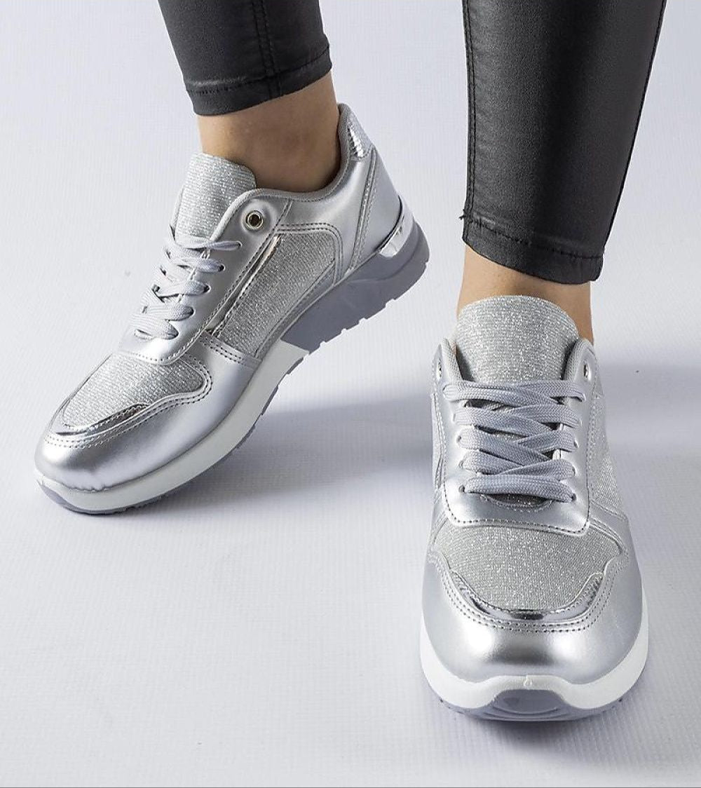 Silver metallic lace-up sneakers paired with black leggings on white background.