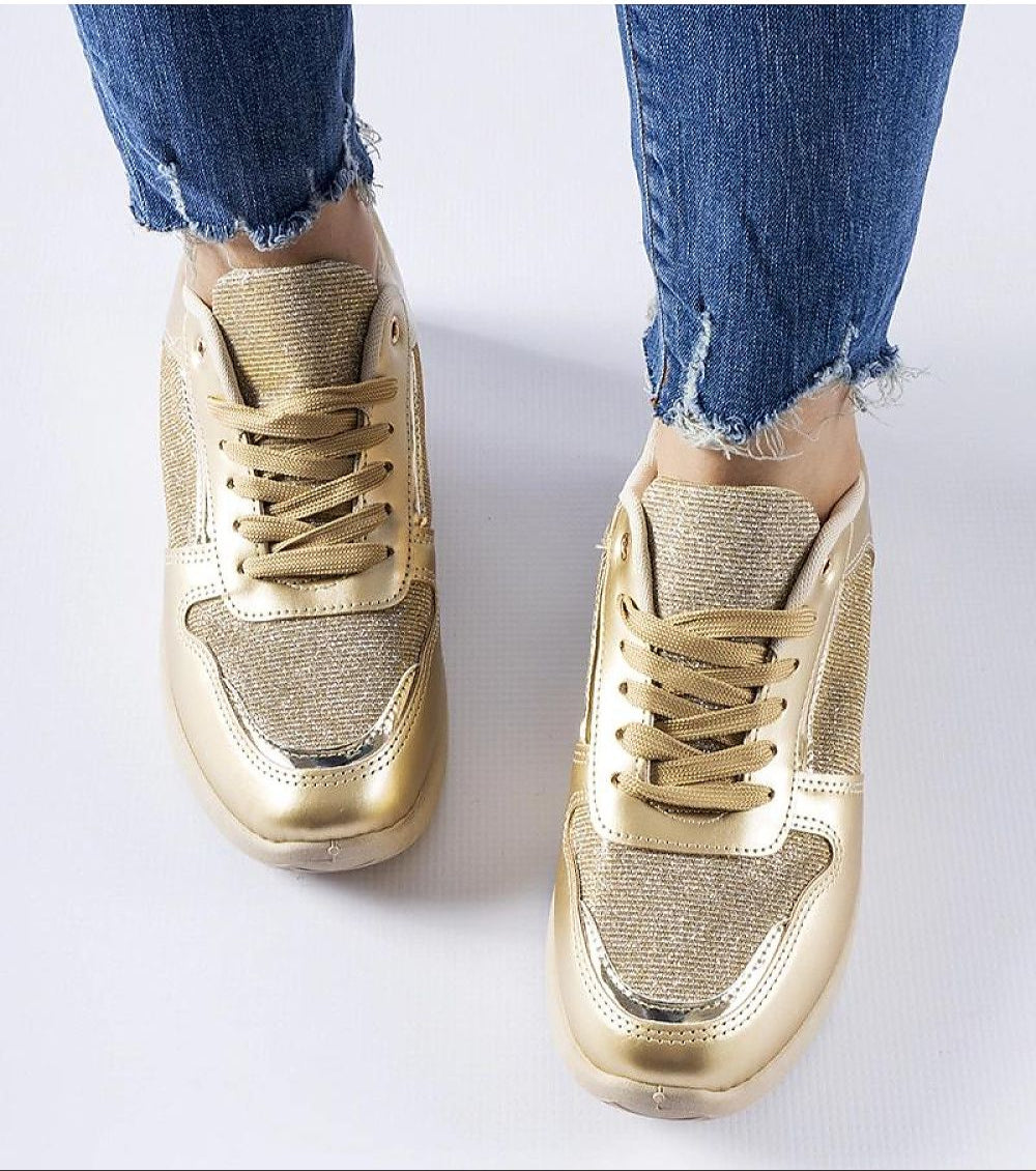 Gold metallic lace-up sneakers with textured design worn with frayed hem jeans, showcasing a stylish and casual look.