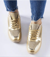 Gold metallic lace-up sneakers with textured design worn with frayed hem jeans, showcasing a stylish and casual look.